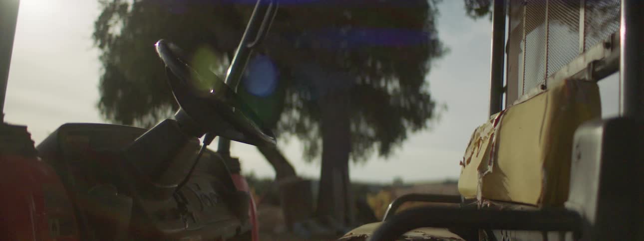 A golf cart with ripped up seats sitting outside