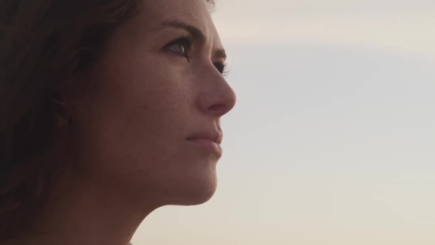 A woman stares ahead as she stands outside