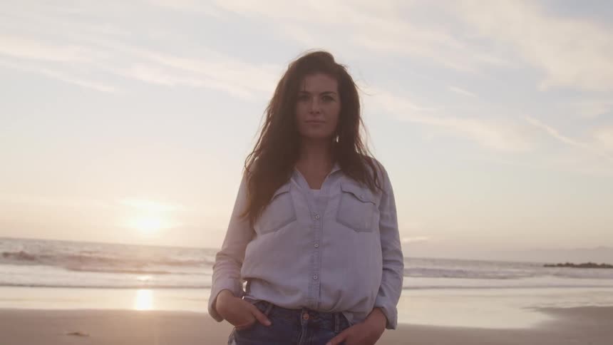 A woman standing on a beach with the ocean and sky in the background