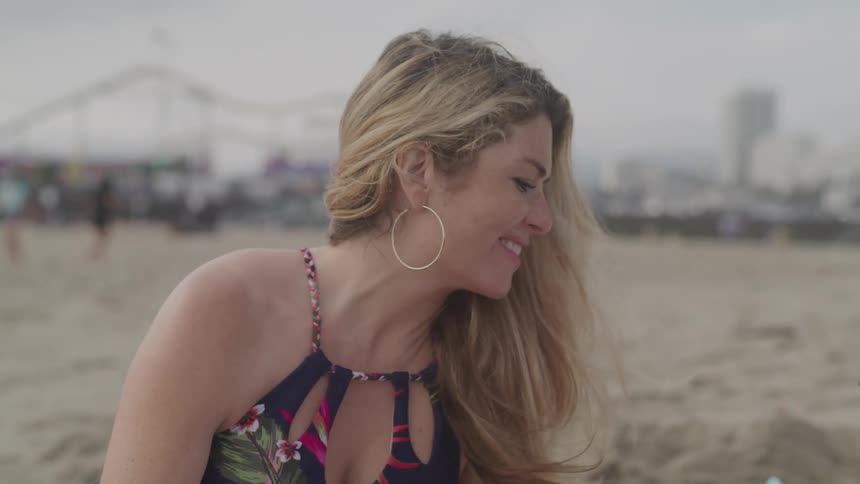 A woman sitting on the beach smiling