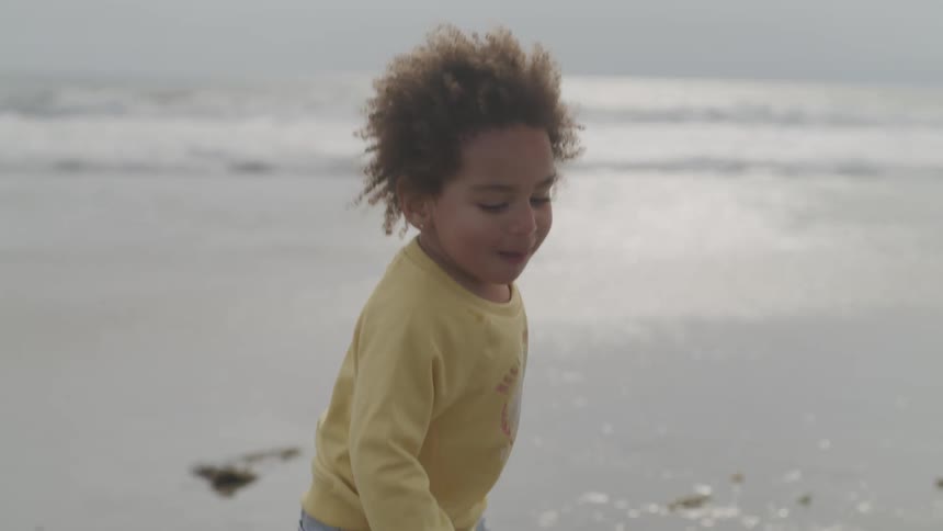 A little girl jumps and plays on the beach