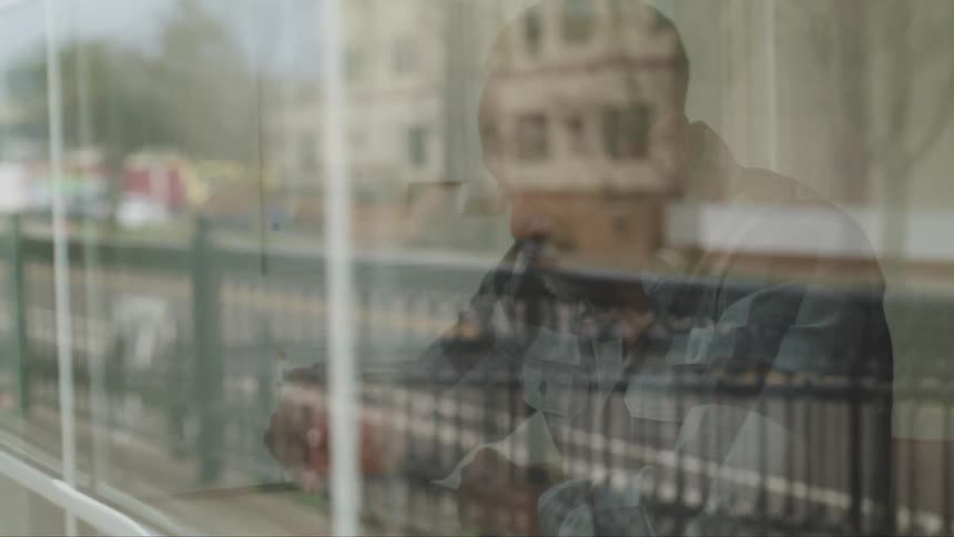 A man sits in a cafe and has a drink while looking out the window