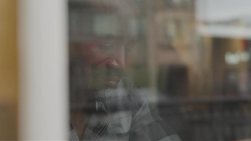 A black male sitting in a cafe drinking from a mug