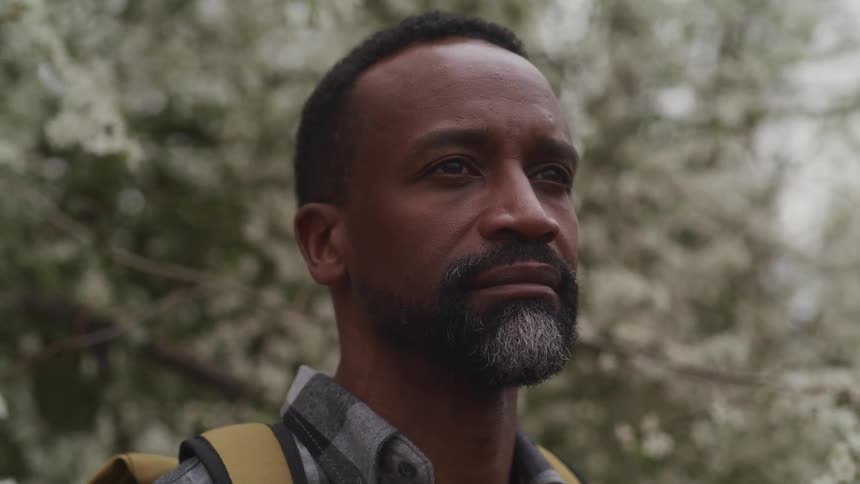 A man is wearing a backpack and standing outdoors