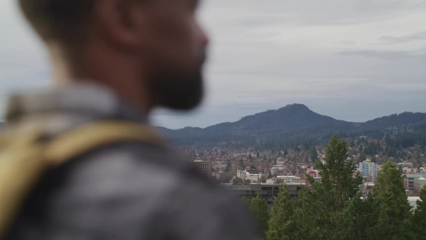 Man looks out at the city and the mountains
