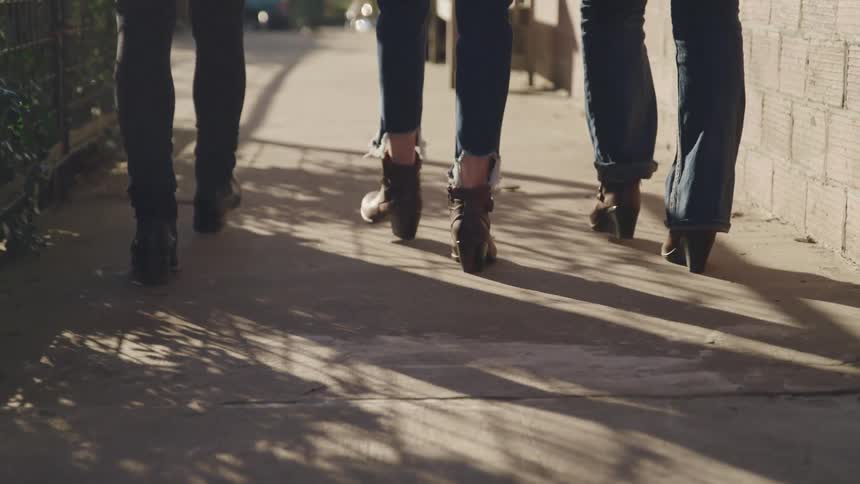 Three people are walking on a sidewalk outdoors