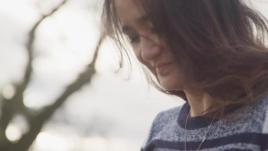 Close up of a woman looking down near a tree outdoors