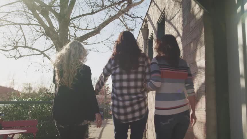 Three women walk past a building during the day