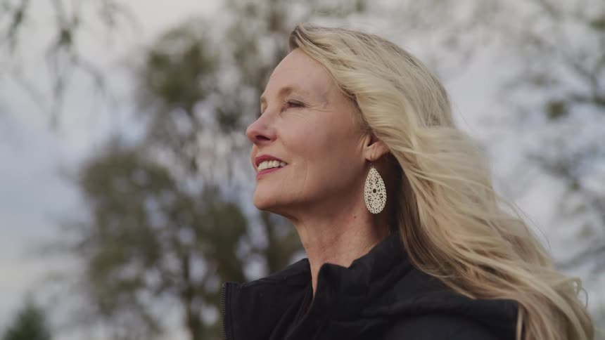 A woman is standing outdoors and smiling