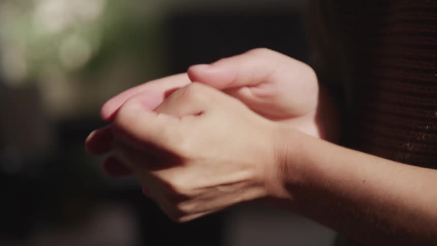 Person rubs hands together using sanitizer while standing outdoors