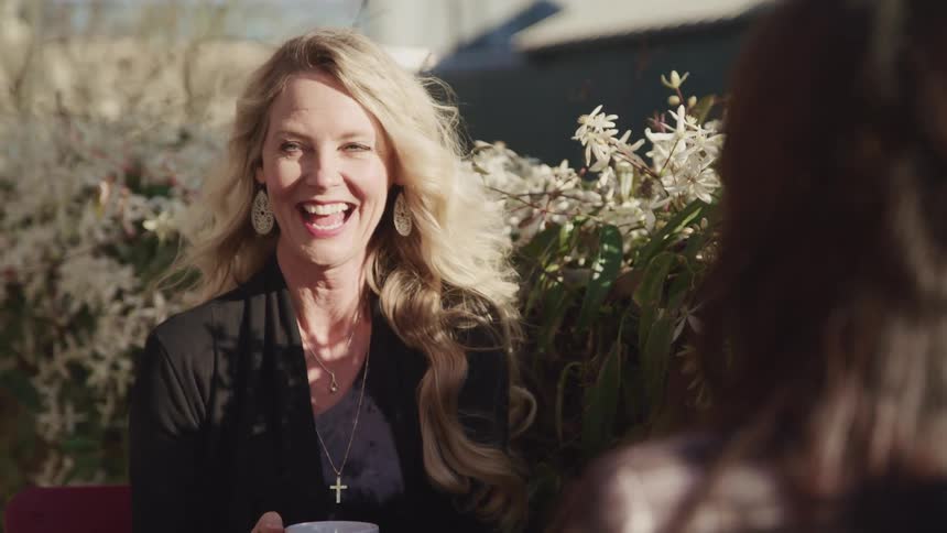Two woman are standing outdoors and smiling
