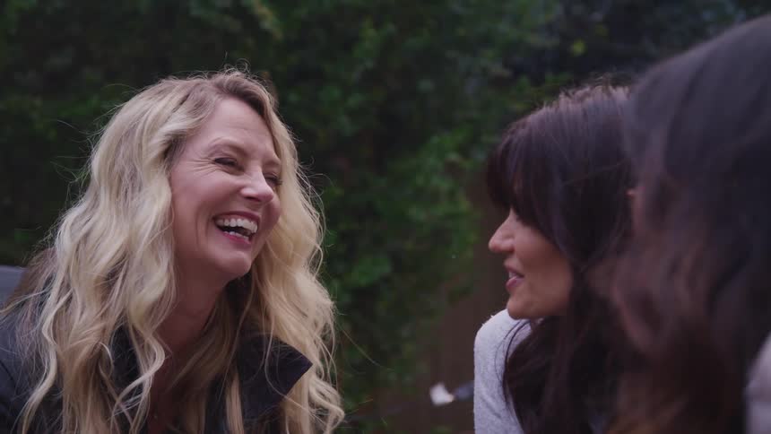 A group of woman laughs and talks while sitting in the backyard