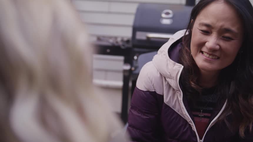 Three teenage girls sit outside a home and talk