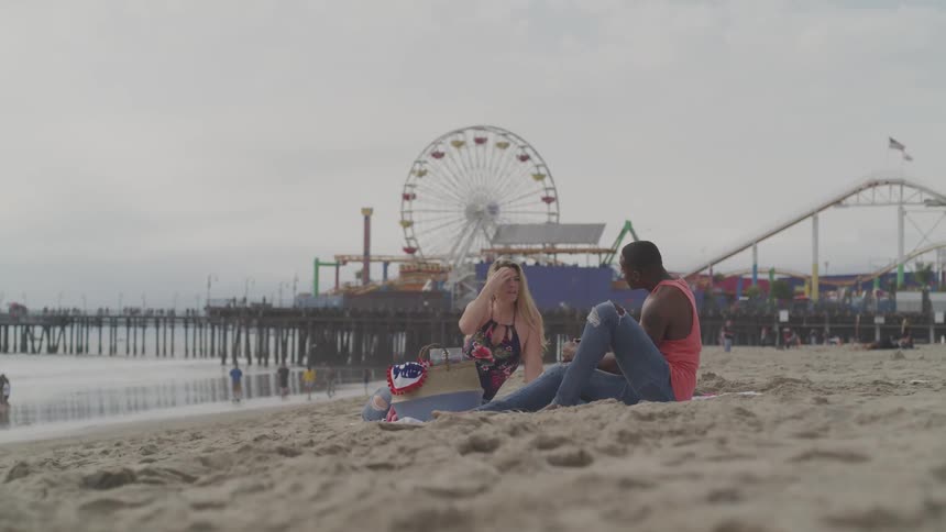 Two people sit on the beach and talk