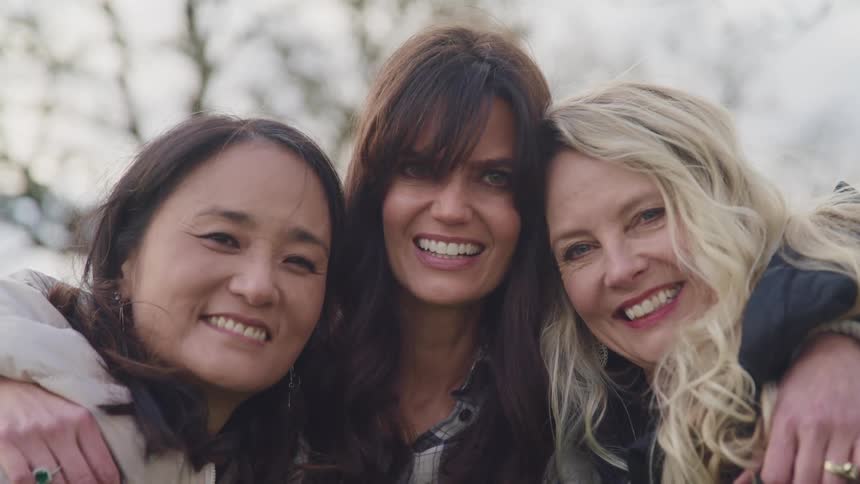 Three women hug and smile together