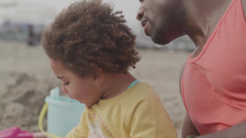 A father and son eat and drink on the beach