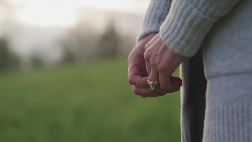 A woman clasps her hands together outside