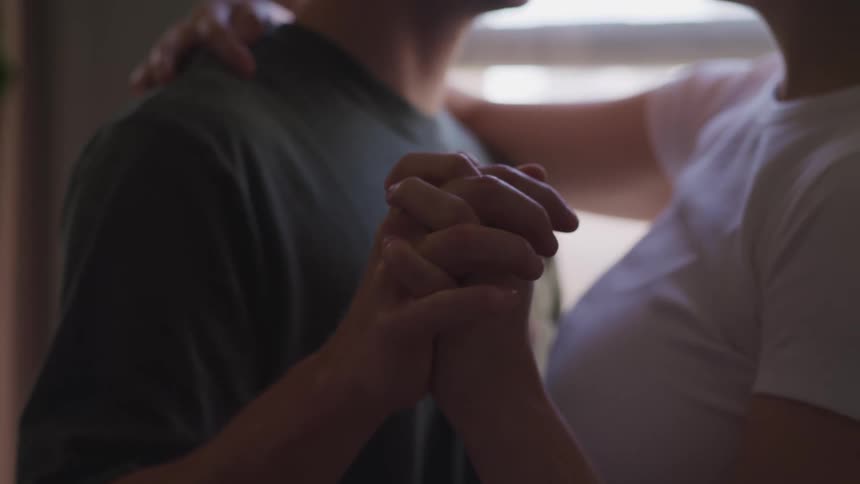 Man with a green t shirt and woman with a white t shirt hold hands and dance together