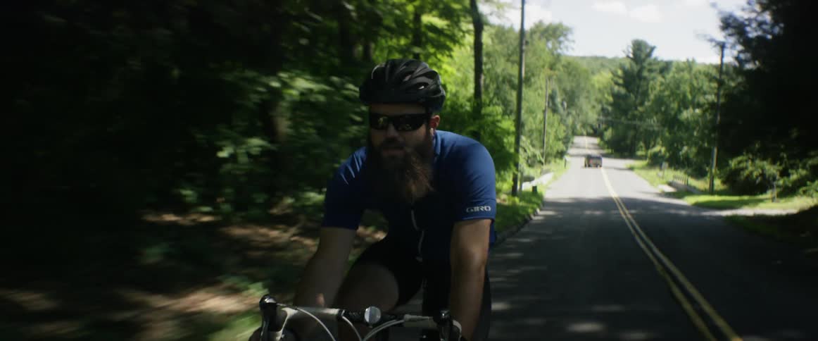 A man bicycles down a rural road on a sunny day