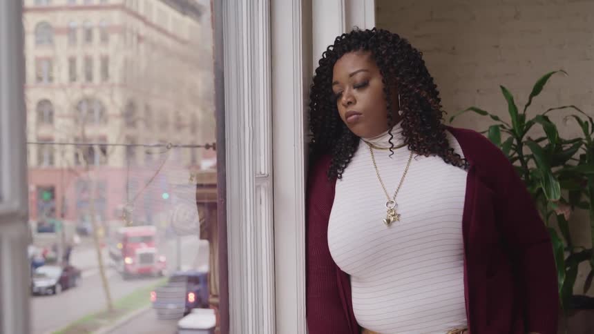 A woman is looking down at the city from her window