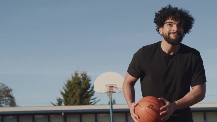 A man outside dribbles a basketball and shoots