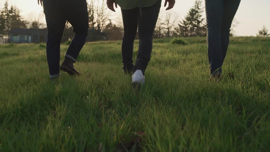A group of friends walks uphill in an open area with green grass