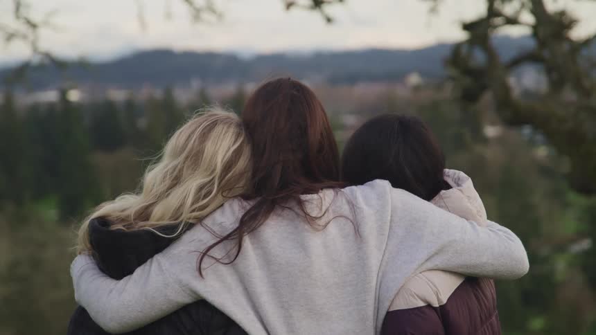 Three women hug on the hill