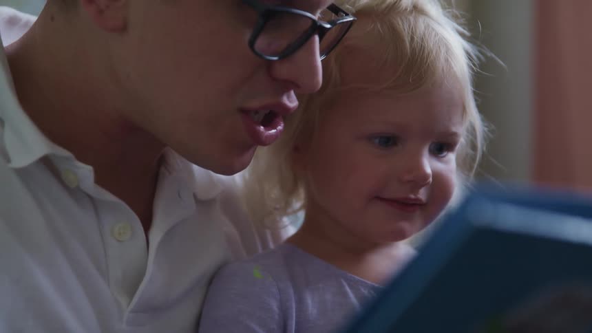 A man is reading a book to a girl