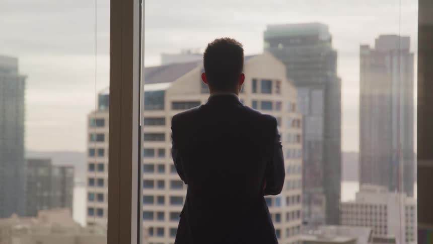 Businessman in a suit looks out the office window in the office