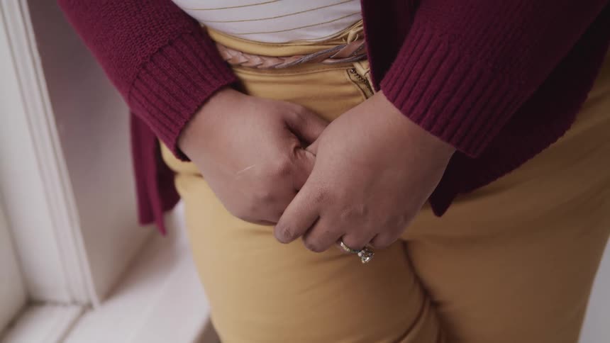 Close up of a woman clutching her hands together in a room