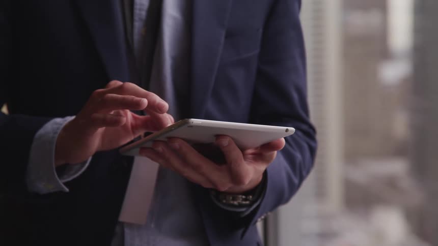 A man standing in his house using a tablet