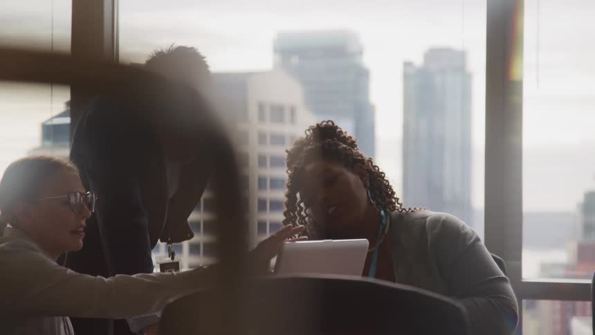 Coworkers look at a laptop and talk