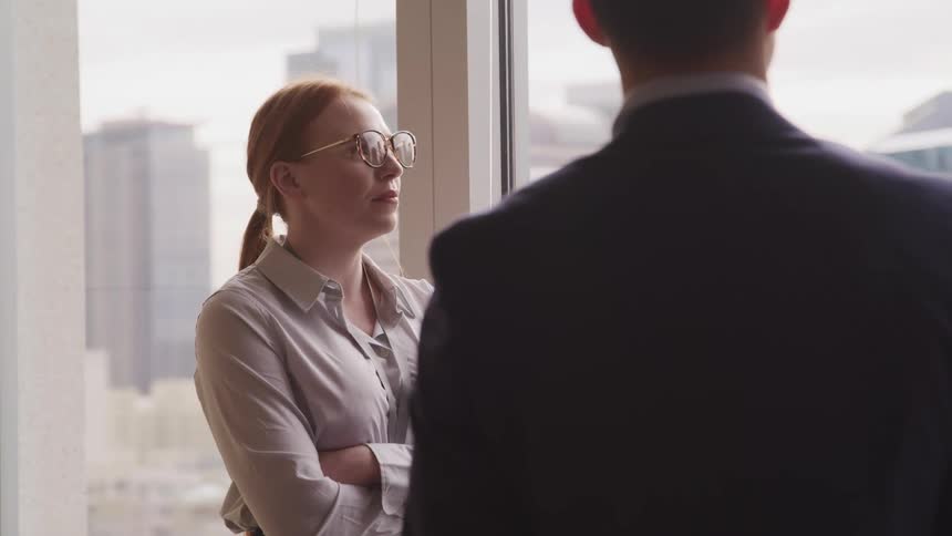 Business people in the office stand near a window in the city