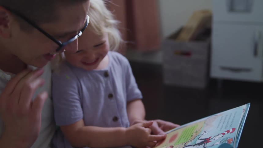 Father and daughter read book the he tickles her