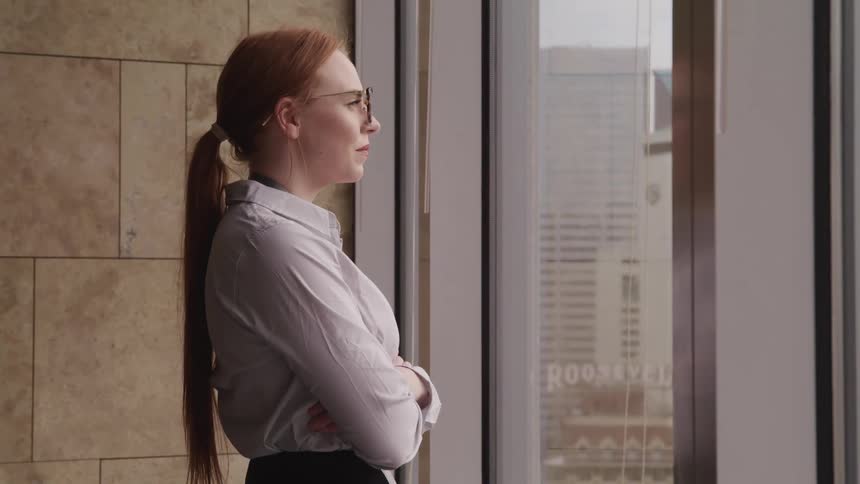 Business woman looks at the city out of the window in the office