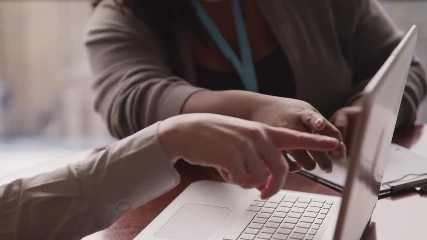 Two people point at a laptop together