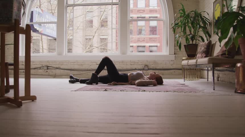 A woman is laying on a rug indoors
