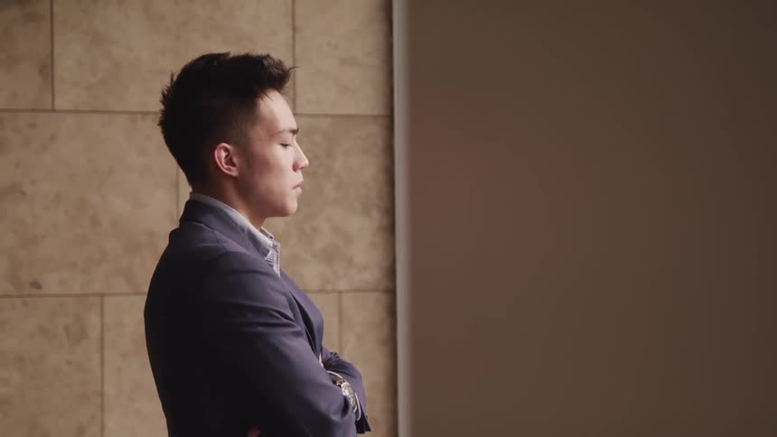 Man in business suit stands looking out window