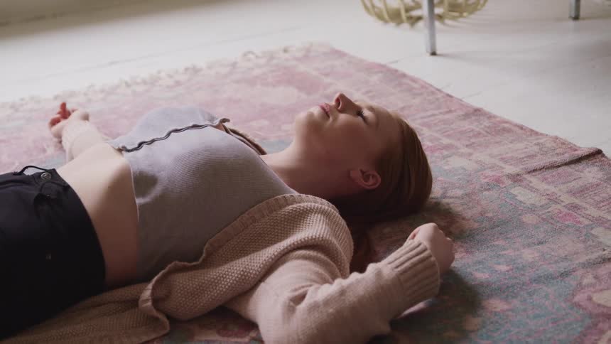 A woman is laying on a rug indoors