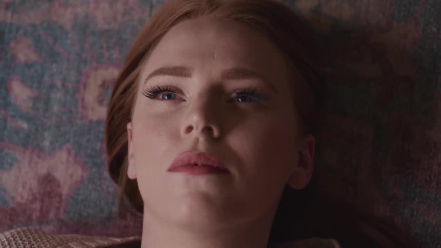 A woman laying on a carpet and opening her eyes