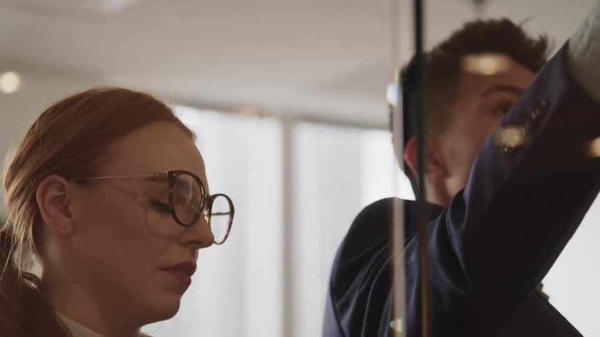 Two people working side by side writing in an office