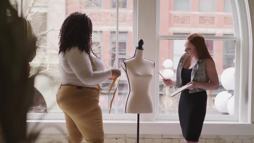 A pair women examine a mannequin in a clothing shop during the day
