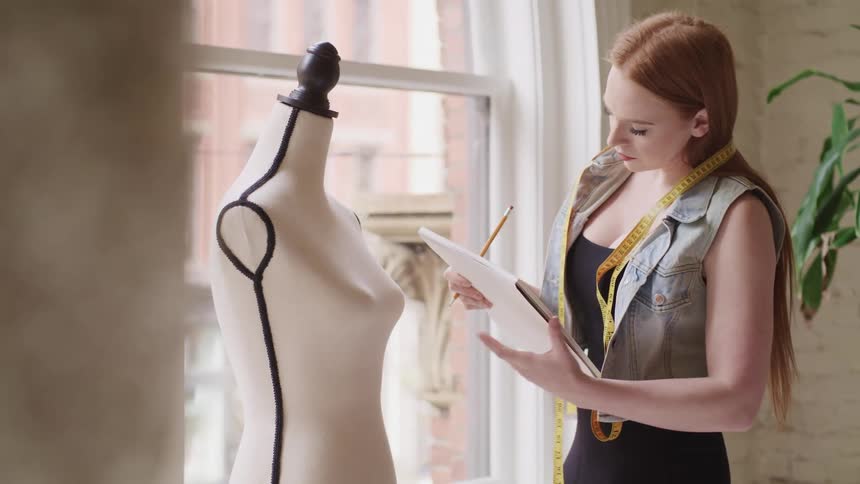A woman looks at a mannequin and writes some information down