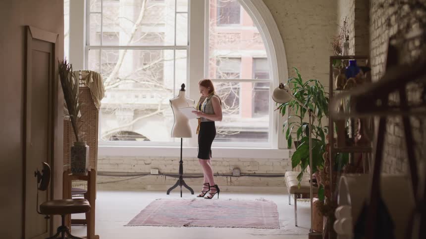 Female fashion designer takes measurements of a mannequin in a studio