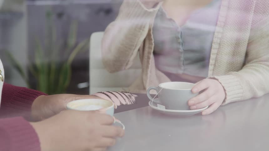 Two women sitting in a cafe drinking coffee and chatting