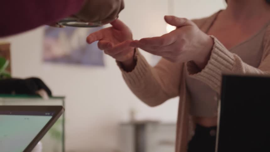 A cashier handing a mug to a customer