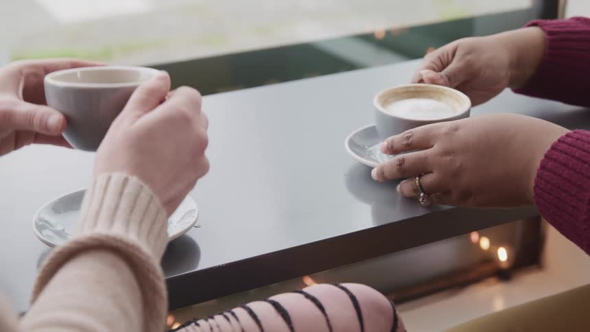 Friends drink coffee and tea in ceramic white cups on the counter of a cafe