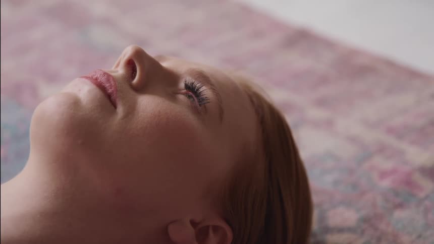 Woman lies on back on rug looking up