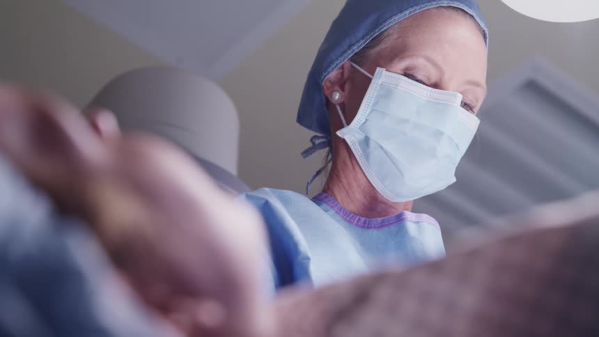 A doctor works on a patient on an operating table