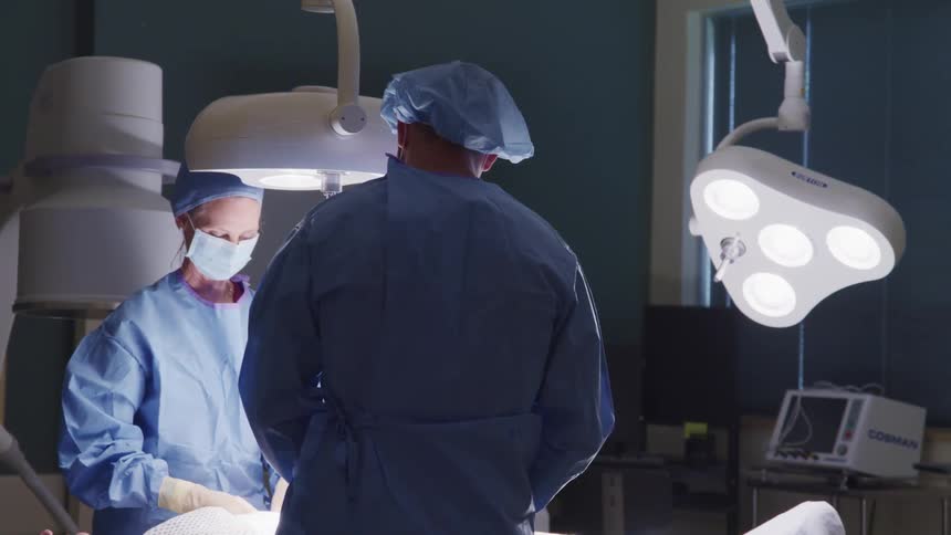 A doctor and nurse work on a patient on an operating table